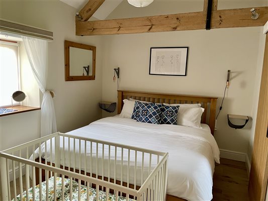 Master bedroom with a white cot at the end of the bed.